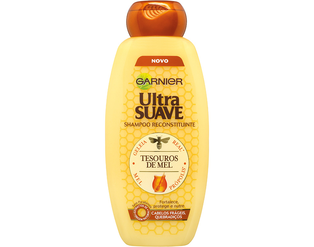 Yellow bottle of Garnier Ultra Suave Honey Shampoo, 400ml, featuring a brown flip-top cap and honeycomb design, emphasizing its nourishing and protective properties.
