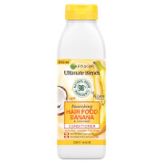 White plastic bottle with a yellow label, featuring illustrations of bananas and coconuts, labeled "Garnier Ultimate Blends Nourishing Hair Food Banana & Coconut Conditioner - 350ml."