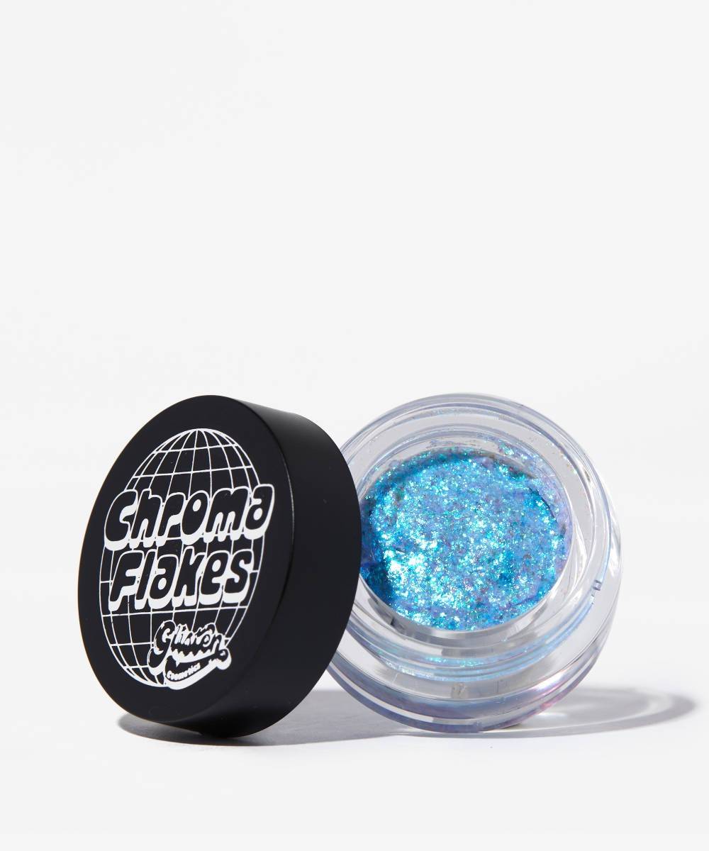 A clear jar of "Chroma Flakes" by Glisten Cosmetics, featuring iridescent blue and silver glitter, with a black lid adorned with a globe graphic and white text.