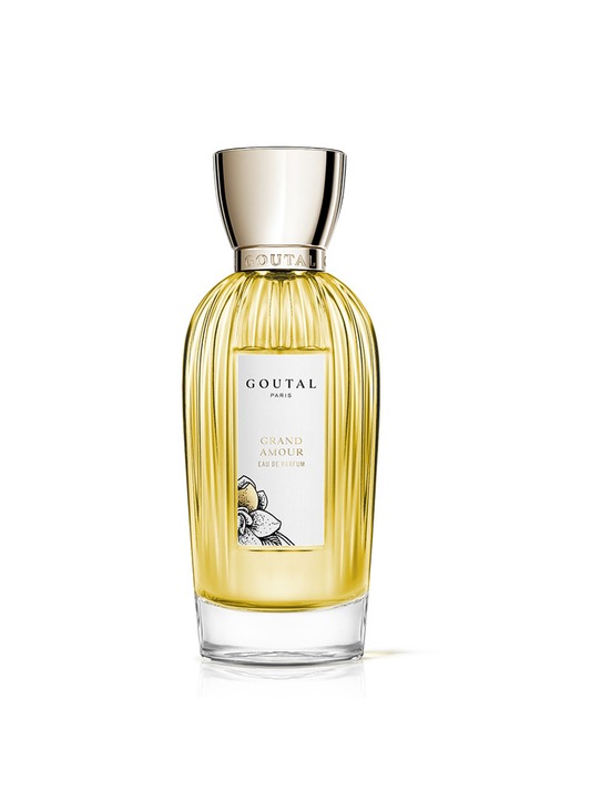 Clear glass perfume bottle with a ribbed design, featuring a silver cap and a white label displaying "GOUTAL GRAND AMOUR" with floral illustrations, containing 50ml of golden fragrance.