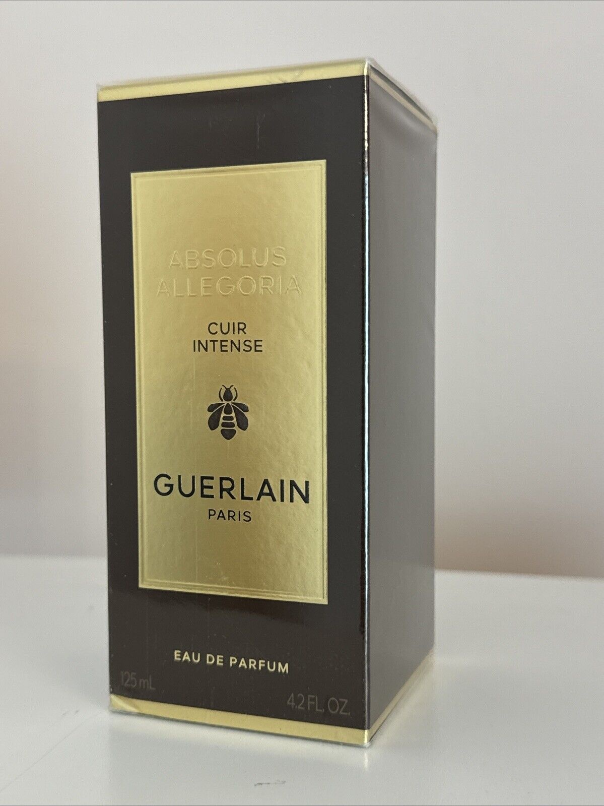 Black box with gold accents, featuring "Absolus Allegoria Cuir Intense" in elegant font, and a bee emblem; 4.2 oz Eau de Parfum for unisex by Guerlain.