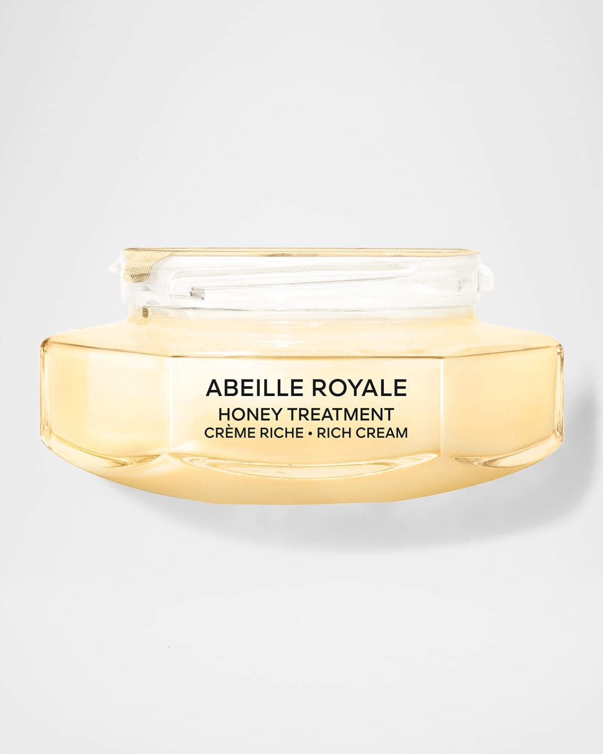 Golden-hued, luxurious cream in a sleek, curved glass jar with a transparent lid, labeled "Abeille Royale Honey Treatment Rich Cream."