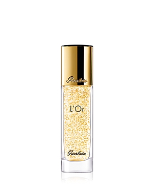 Clear glass bottle containing a golden liquid with gold flakes, topped with a sleek gold cap, featuring the brand name "Guerlain" and "L'Or" elegantly printed on the front.