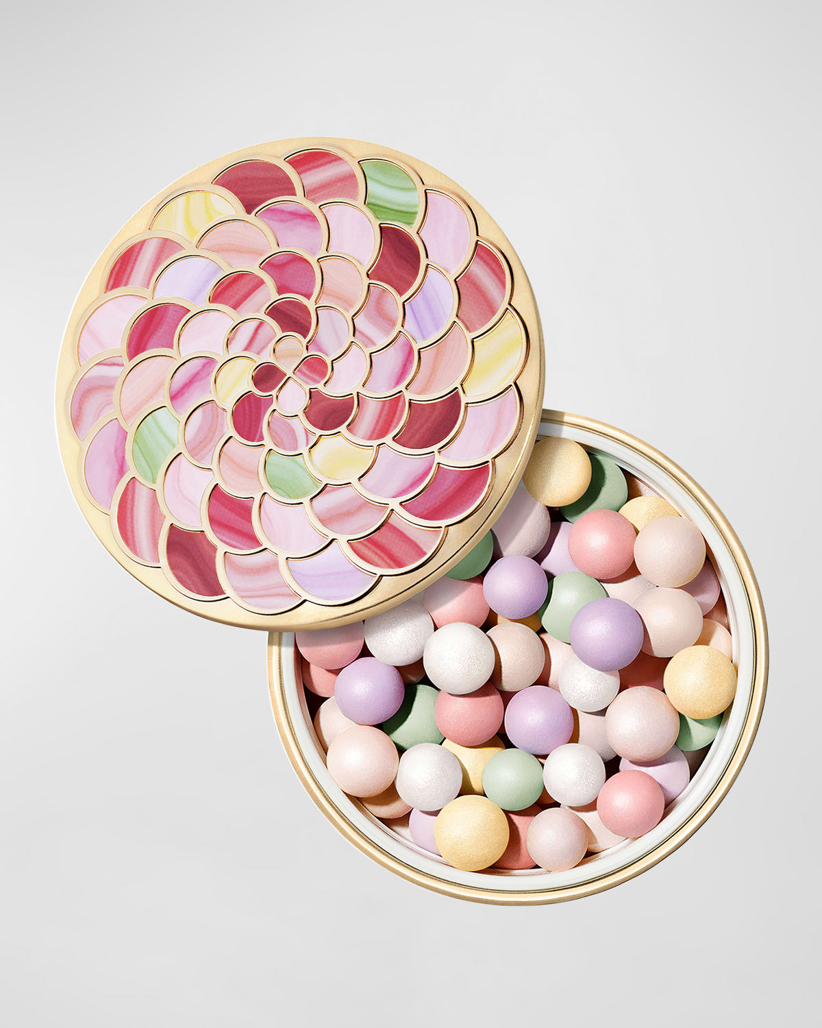 Round, gold compact featuring a colorful floral design on the lid, filled with pastel-colored, spherical powder pearls in pink, lavender, green, and yellow hues.
