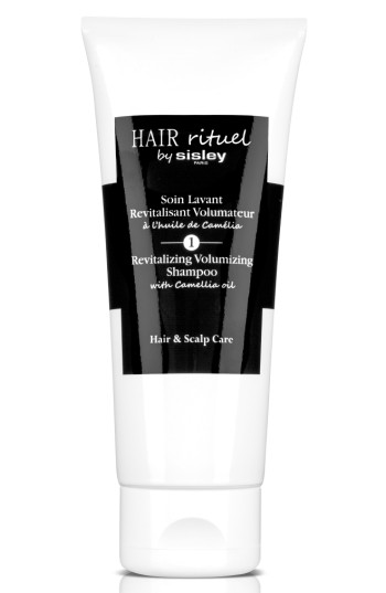 White tube with a sleek design featuring a black label, displaying "Hair Rituel by Sisley" and "Revitalizing Volumizing Shampoo with Camellia Oil" in elegant font.