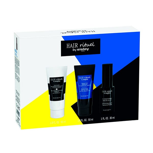 Three hair care products in a box featuring a white tube, a black tube, and a black spray, set against a colorful geometric background of blue and yellow.