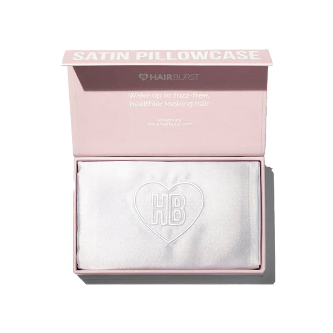 White satin pillowcase with an embossed "HB" heart logo, presented in a light pink box featuring the Hairburst brand name and a slogan about healthier hair.