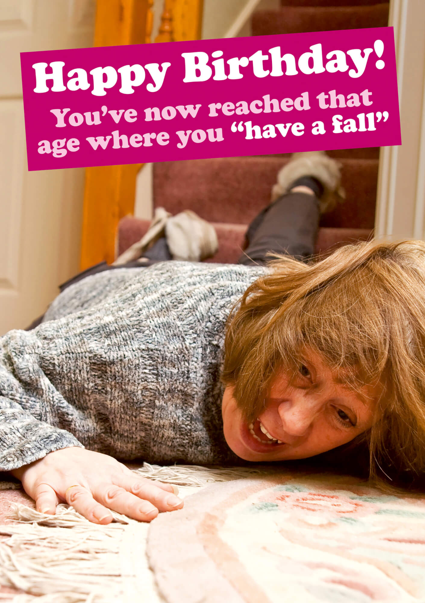 A humorous birthday card featuring a woman in a gray sweater comically falling on a staircase, with bold pink text reading, "Happy Birthday! You've now reached that age where you 'have a fall'."