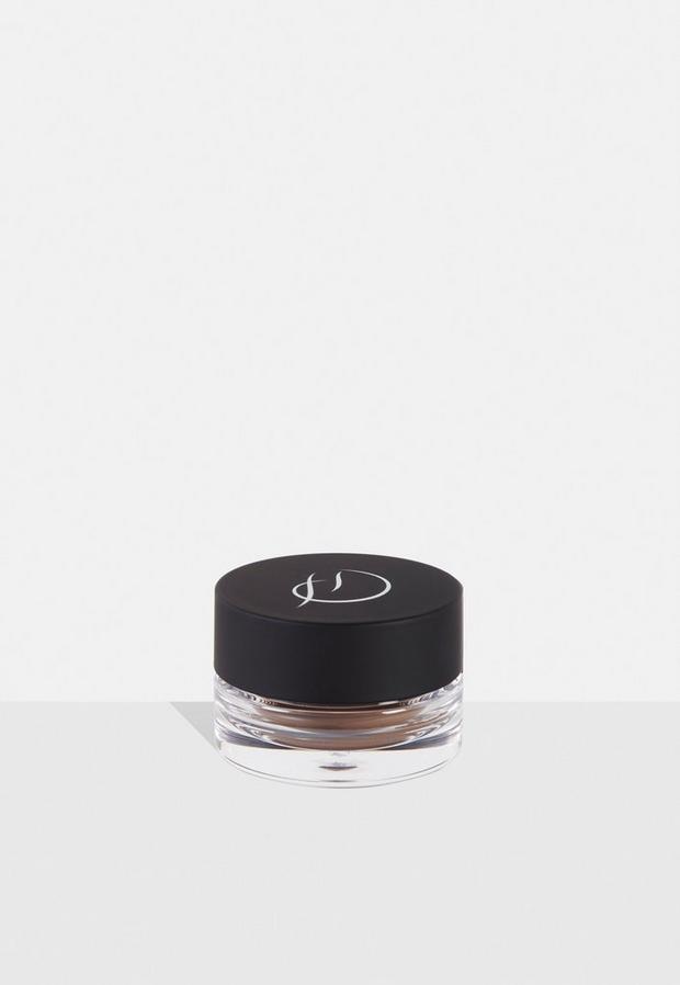 Brow Crème Bombshell by HD Brows in a clear glass jar with a matte black lid, featuring the brand's logo in white, showcasing a rich, warm brown crème inside.