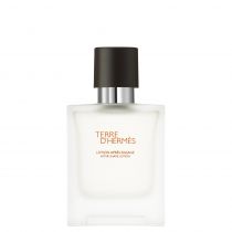 Clear glass bottle with a square shape, featuring a black cap and silver neck, labeled "Terre D'Hermès Aftershave Lotion" in orange and black text.
