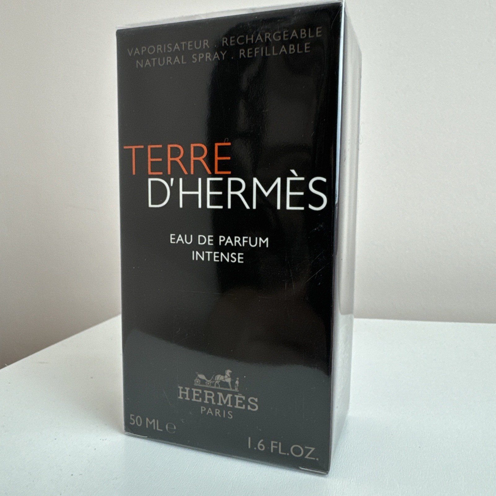 Black rectangular box with a glossy finish, featuring bold red text reading "TERRE D'HERMÈS" and "EAU DE PARFUM INTENSE," alongside Hermès branding and volume details.