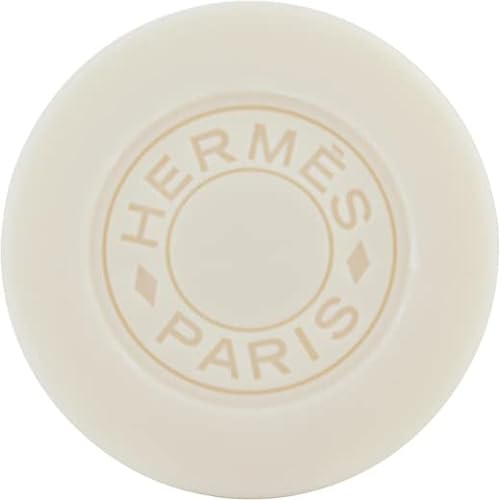 Round, creamy white soap with a subtle embossed "Hermès Paris" logo in the center, featuring a smooth surface and elegant, minimalist design.