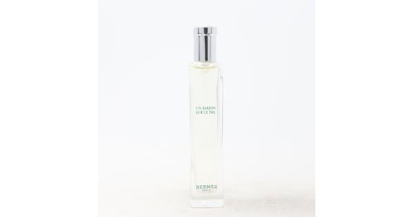Clear glass bottle of "Un Jardin Sur Le Nil" Eau De Toilette by Hermès, featuring a silver cap and minimalist design with green text on the front, holding 0.5 oz of fragrance.