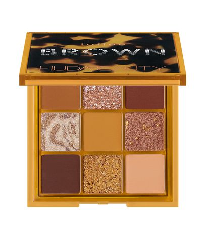 Huda Beauty Brown Obsessions Eye Palette in Toffee features nine shades in warm browns, golds, and a soft beige, housed in a square, vibrant yellow compact with a clear lid.