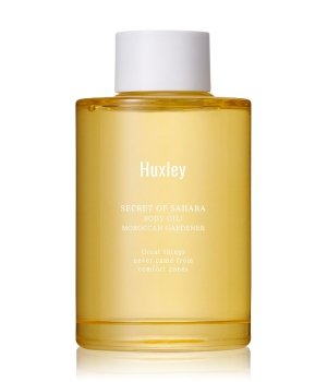 Transparent bottle of Huxley's "Hu" body oil, featuring a bright yellow liquid, minimalist design, and a white cap, labeled "Secret of Sahara" with Moroccan argan oil.