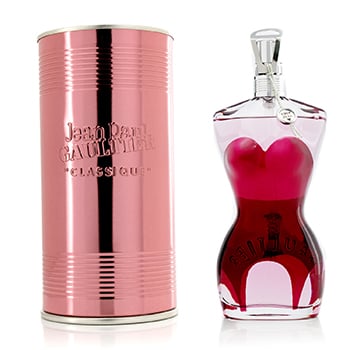 Pink cylindrical box with silver accents beside a clear glass bottle shaped like a woman's torso, featuring a pink heart-shaped design and a silver cap.