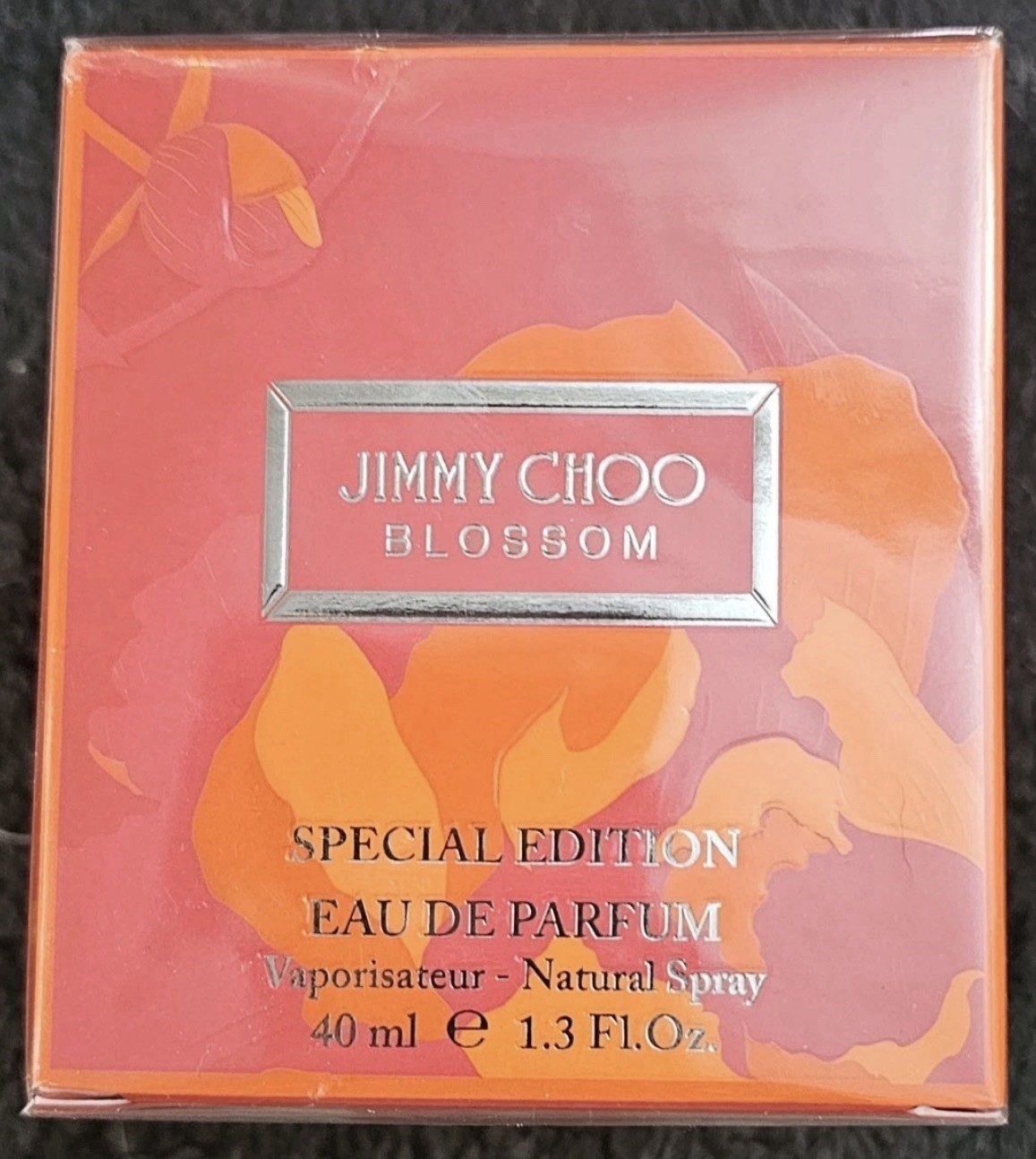 Bright orange box featuring floral designs, silver logo, and text indicating "Jimmy Choo Blossom Special Edition Eau De Parfum 40ml Spray."