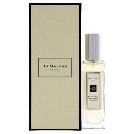 Clear glass bottle with a silver cap, containing Jo Malone English Oak & Hazelnut Eau De Cologne, presented in a sleek beige and black box.