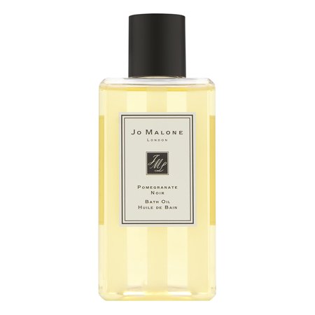 Clear bottle of Jo Malone London Pomegranate Noir Bath Oil, featuring a black cap and elegant label with gold accents, filled with light yellow bath oil.