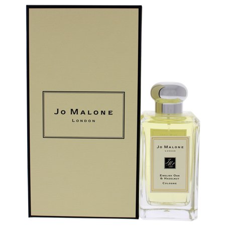 Clear glass bottle with a round silver cap, featuring a yellow liquid inside, accompanied by a cream-colored box with black accents and the Jo Malone London logo.