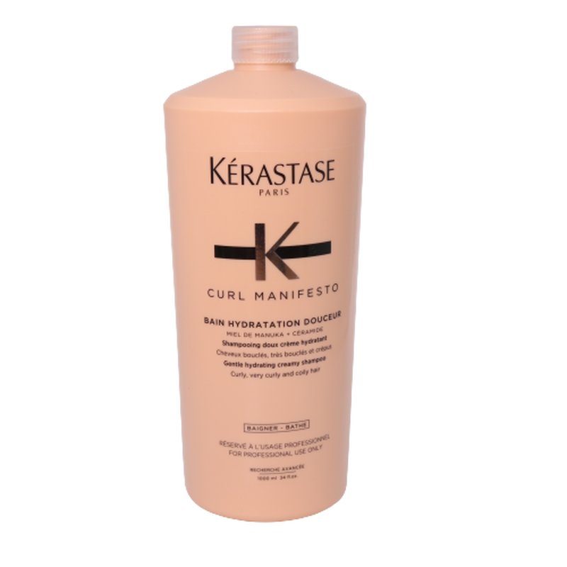 Light peach-colored, large salon-sized bottle of Kérastase Curl Manifesto Bain Hydratation Douceur Shampoo, featuring a sleek design and black logo, suitable for curly and coily hair.