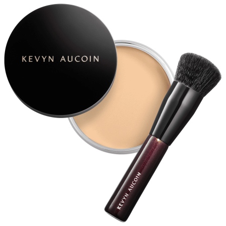 Kevyn Aucoin Foundation Balm in a sleek black compact with gold lettering, revealing a vibrant orange balm and accompanied by a black brush.