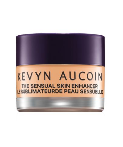 Debenhams The Sensual Skin Enhancer in Sx7, a creamy foundation in a glass jar with a purple lid, featuring a smooth, peachy beige shade for enhancing skin tone.
