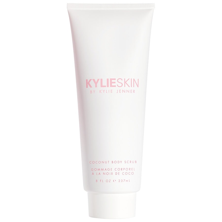 White tube with a pink label reading "KYLIESKIN by Kylie Jenner," featuring "COCONUT BODY SCRUB" text, 237ml size, sleek design, and a flip-top cap.