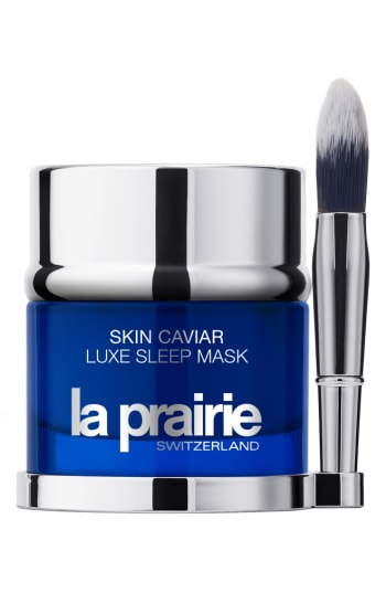 Blue glass jar with a silver lid, labeled "Skin Caviar Luxe Sleep Mask" by La Prairie, accompanied by a small applicator brush.