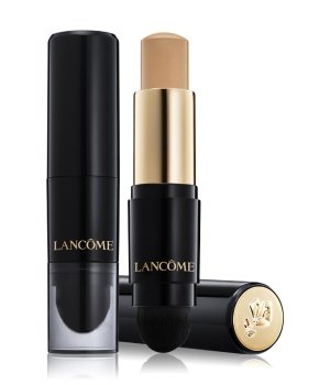 Lancôme Teint Idole Ultra Wear Stick Foundation in Nude, featuring a sleek black and gold design with a twist-up stick and a sponge applicator on the end.
