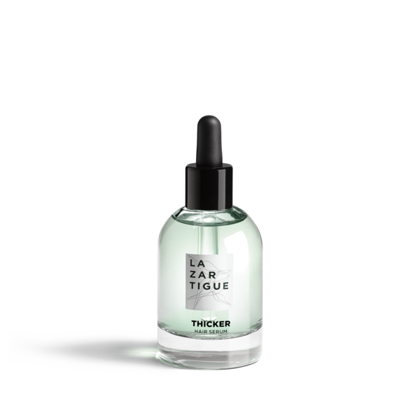Clear glass bottle with a black dropper cap, featuring a light green serum inside and a label that reads "LAZARTIGUE THICKER HAIR SERUM" in bold black text.