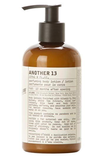 Brown glass bottle with a black pump, labeled "Another 13 Hand and Body Lotion," 237ml, featuring a minimalist design and details about ingredients and usage instructions.