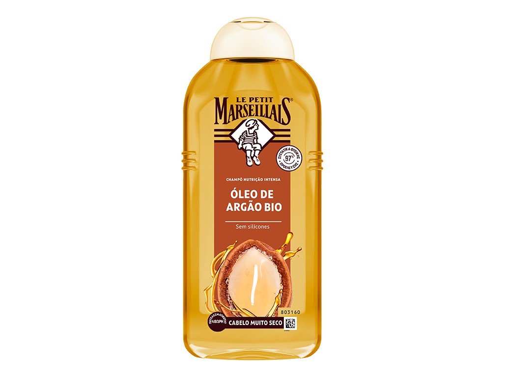 Transparent bottle of Le Petit Marseillais Óleo Argão, featuring a golden liquid, with a beige cap and a label showcasing an argan nut and the brand logo.