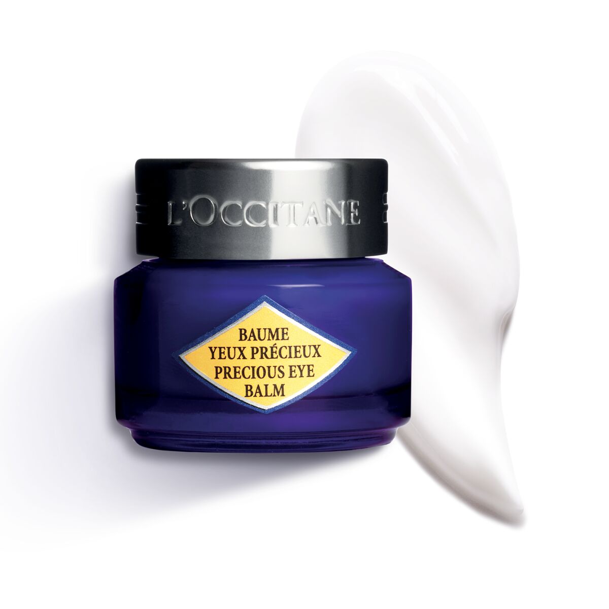 L'Occitane Immortelle Precieuse Eye Balm in a small, deep blue glass jar with a silver lid, featuring a yellow and blue label, alongside a smooth, white balm swatch.