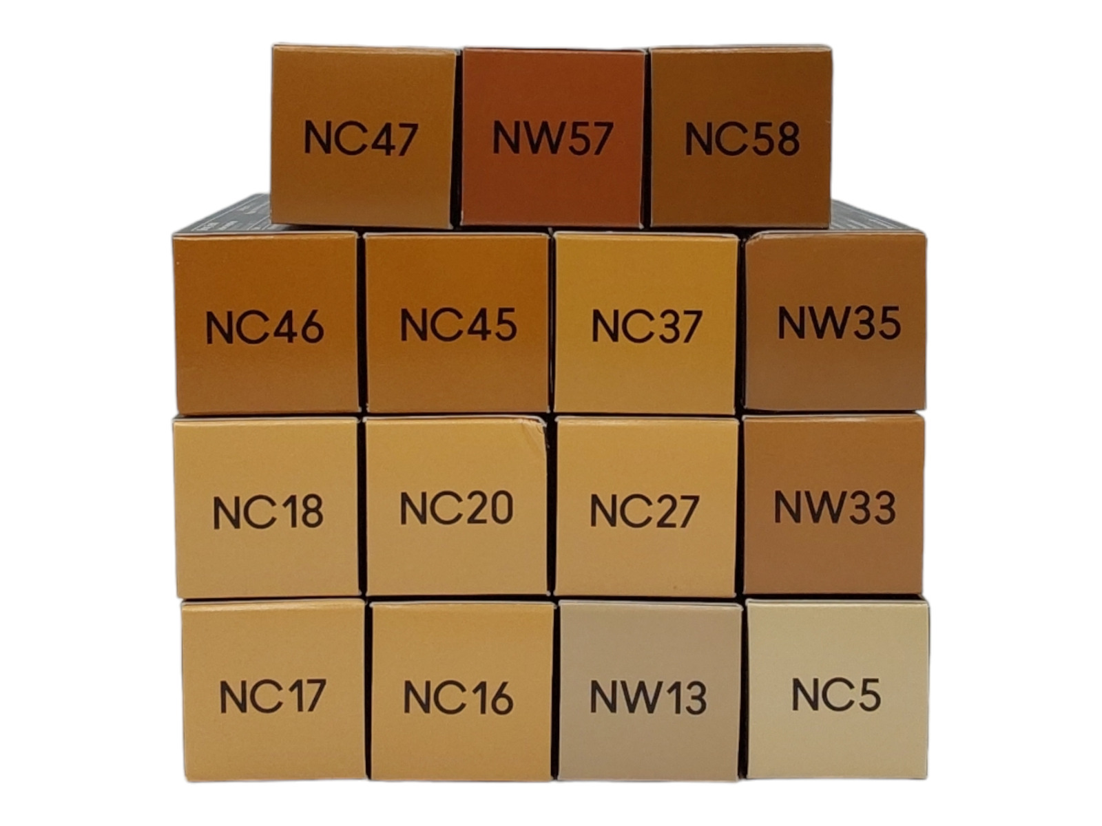 Stacked foundation boxes in various shades, labeled with codes like NC47, NW57, and NW58, showcasing a range of skin tones from light to deep.