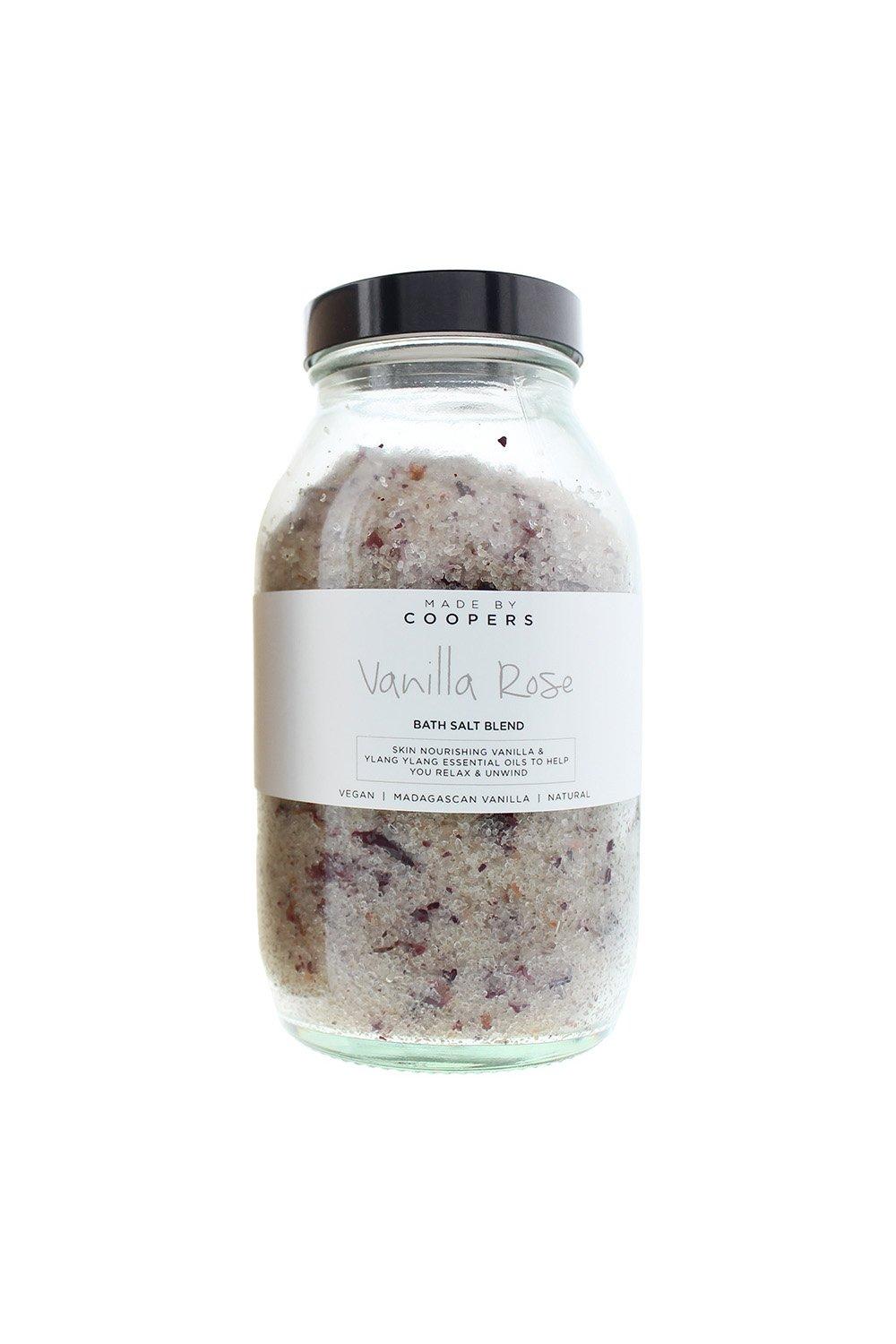 Clear glass jar filled with a pinkish-white bath salt blend, featuring dried rose petals, labeled "Vanilla Rose Bath Salt Blend" with a black and white design.
