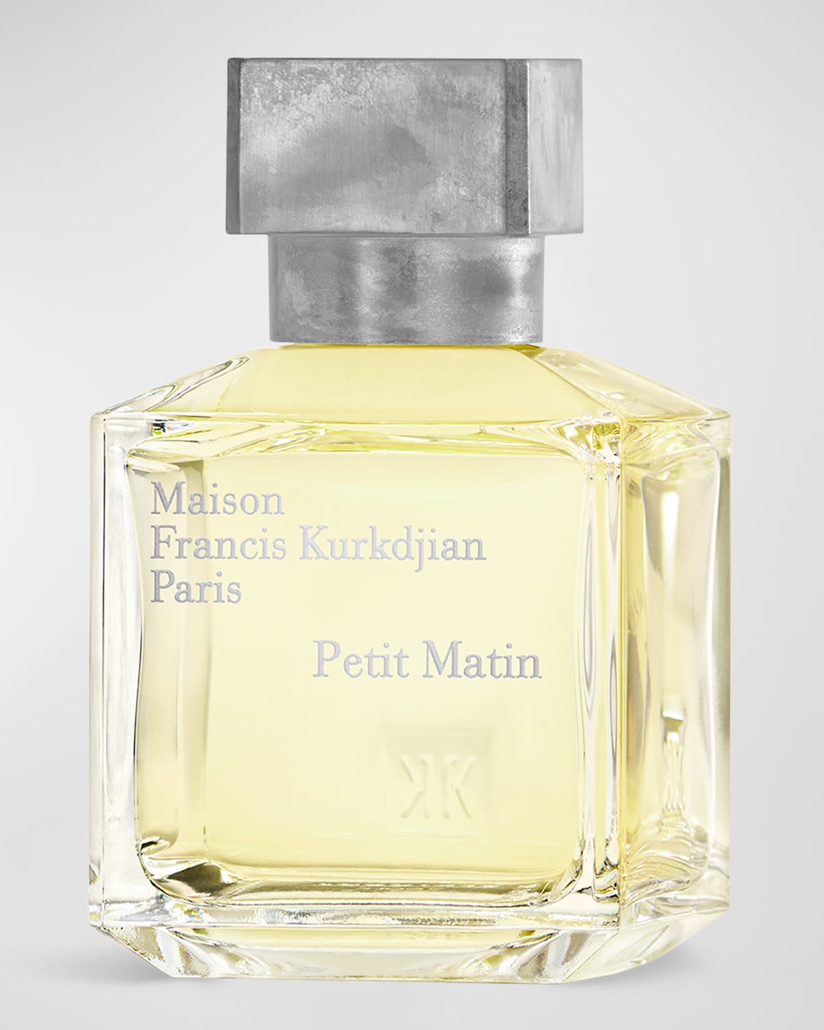 Clear glass perfume bottle with a square silver cap, featuring embossed text "Maison Francis Kurkdjian Paris Petit Matin" on the front and a light yellow fragrance inside.