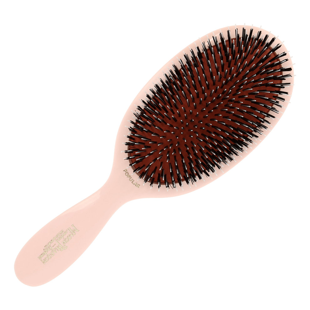 Large Mason Pearson hairbrush featuring a pink handle, a cushioned oval base, and a mix of bristle and nylon bristles for effective detangling.