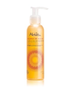 Transparent bottle of Melvita's Source De Roses Milky Cleansing Oil, featuring a pump dispenser, with a golden-yellow liquid and a spiral floral design on the label.
