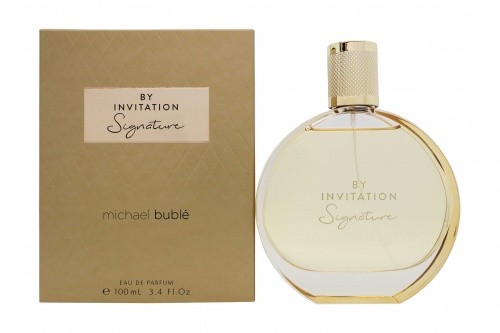 Clear glass bottle with a round shape, featuring a gold cap, alongside a beige box with gold lettering reading "By Invitation Signature" and "Michael Bublé."