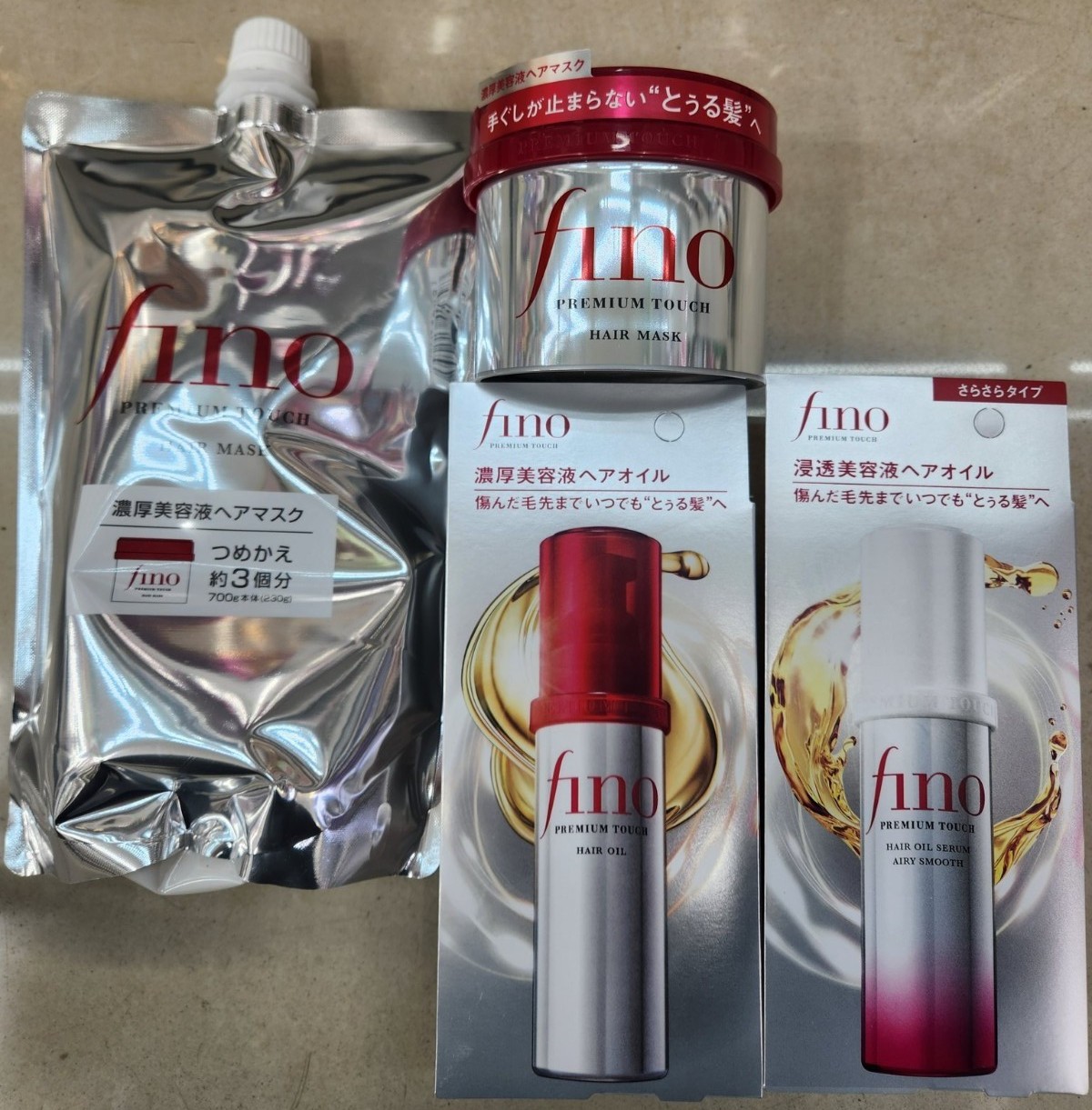 Shiseido FINO Premium Touch Hair Mask jar with a silver and red design, two hair oil bottles in red and white packaging, and a refill pouch, all from Mii Cosmetics.