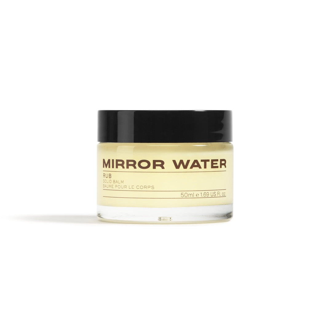 Clear glass jar with a black lid, containing a solid balm with a light yellow hue, labeled "MIRROR WATER RUB" in bold black text, 50 ml size.