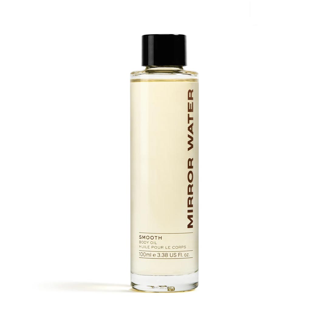 Clear glass bottle with a black cap, containing light yellow body oil, labeled "MIRROR WATER Smooth Body Oil" in bold brown text, 100ml size.