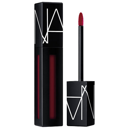 Nars Powermatte Pigment in "Under My Thumb," featuring a sleek black tube with white branding, a pointed applicator, and a deep red liquid matte formula.