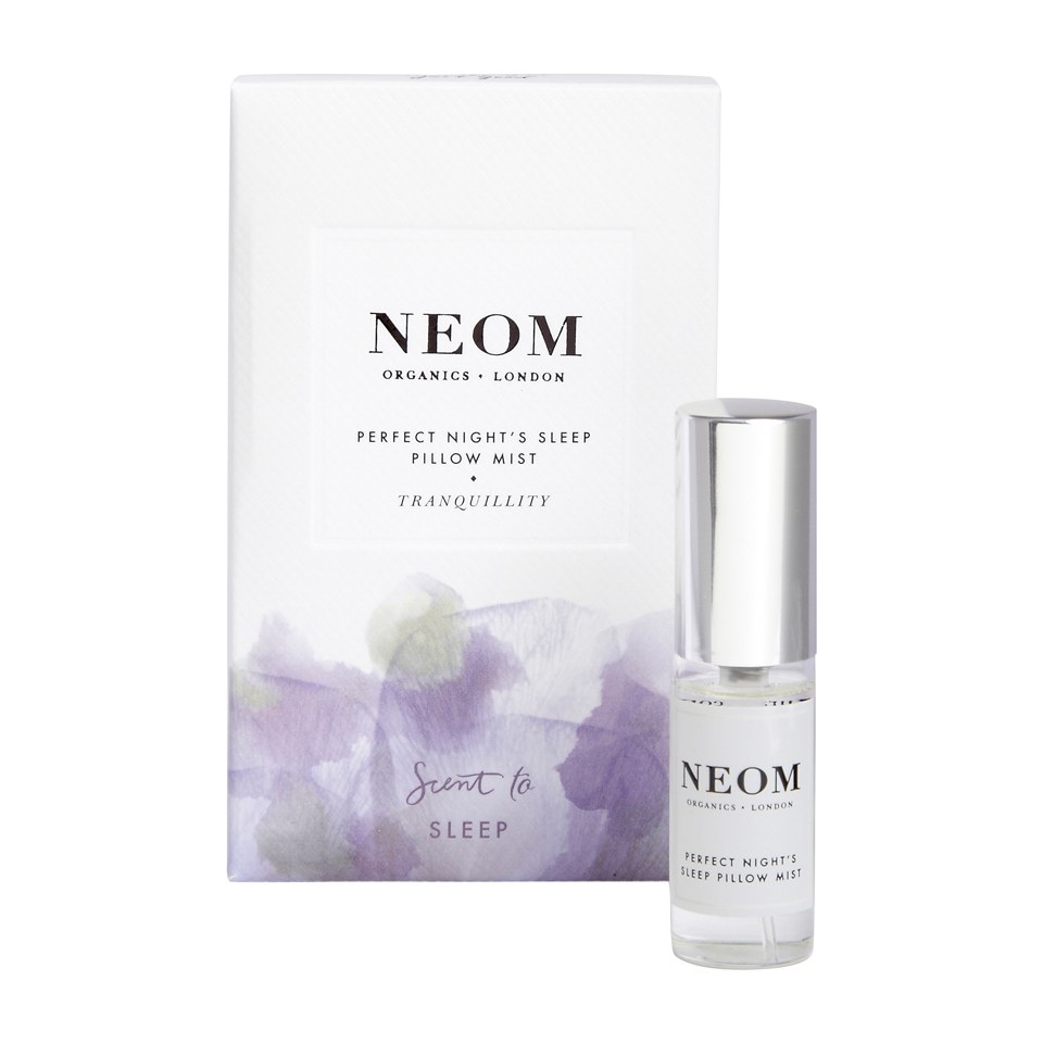 Clear glass spray bottle with silver cap, labeled "NEOM Perfect Night's Sleep Pillow Mist," alongside a white box featuring soft purple floral designs and the brand name prominently displayed.