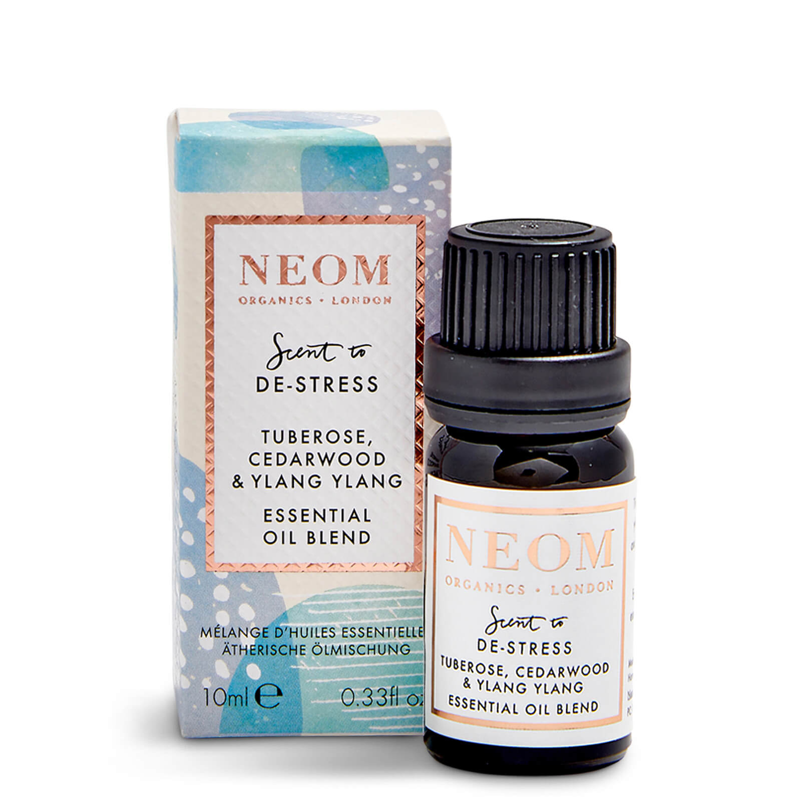 Neom Wellbeing essential oil blend in a dark glass bottle with a black cap, featuring a white and gold label, alongside a colorful box with blue and green accents.