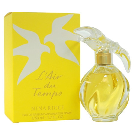Clear glass bottle with a bird-shaped stopper, filled with yellow perfume, beside a bright yellow box featuring white doves and the text "L'Air du Temps" by Nina Ricci.