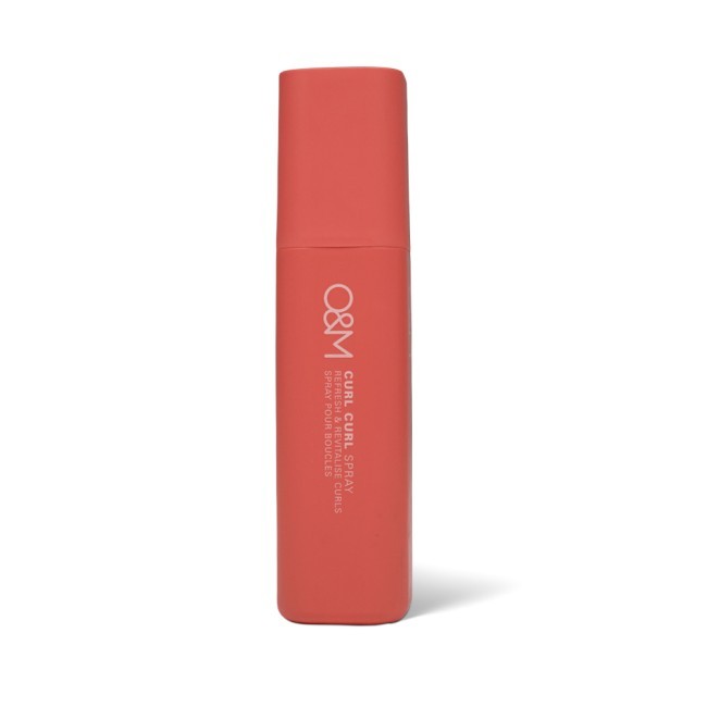 Coral-colored spray bottle with a sleek, matte finish, featuring a square cap and white text that reads "O&M Curl Curl Spray Curl Definition Spray 150 Ml."