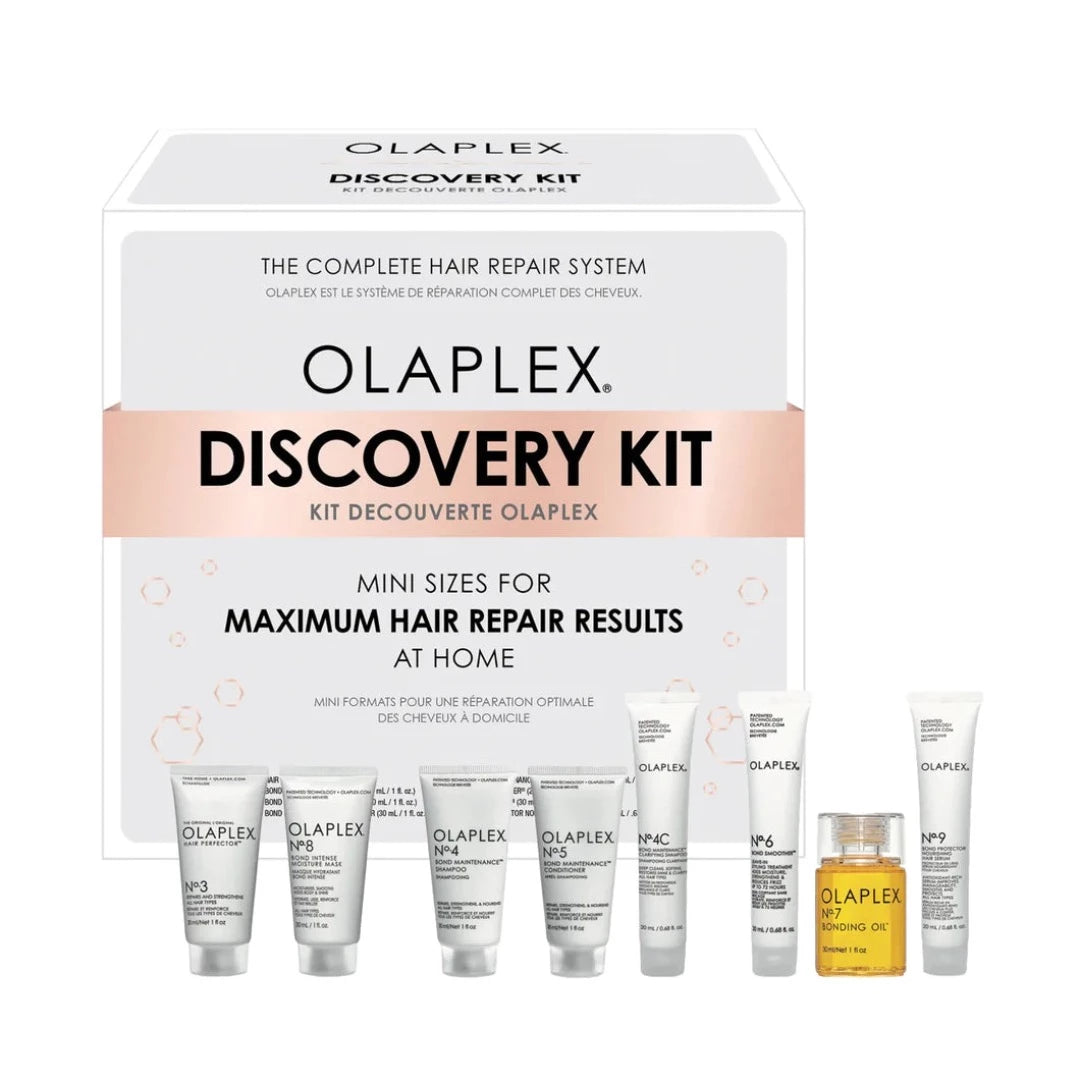 Olaplex Discovery Kit featuring eight mini hair care products in sleek tubes and a small bottle, all displayed in a white box with pink accents and text highlighting hair repair benefits.