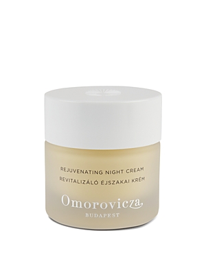 A sleek, frosted glass jar containing Omorovicza Rejuvenating Night Cream, featuring a white lid and elegant branding in silver, with a light cream-colored product inside.